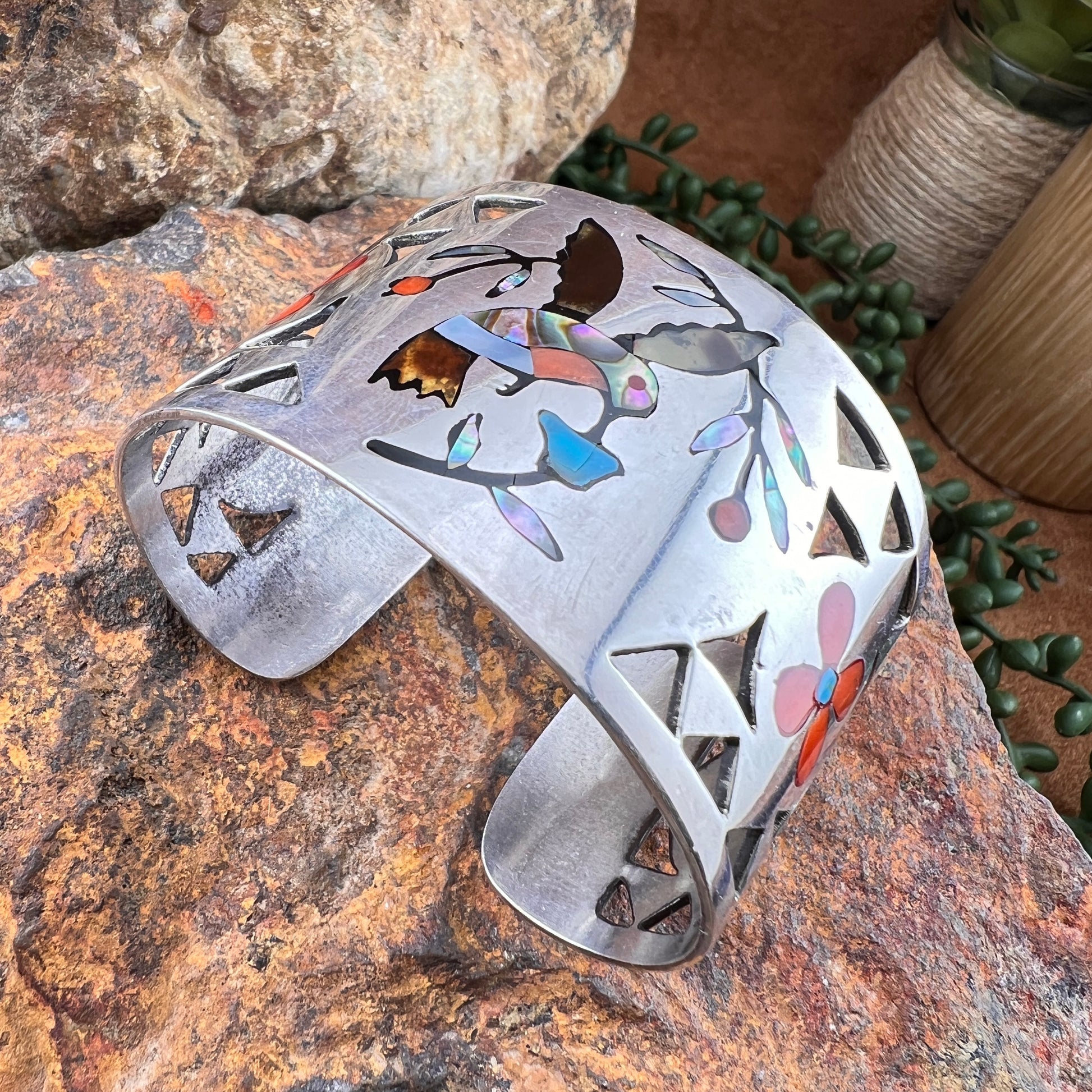 Decorative metal bracelet with cut-out designs on a stone surface