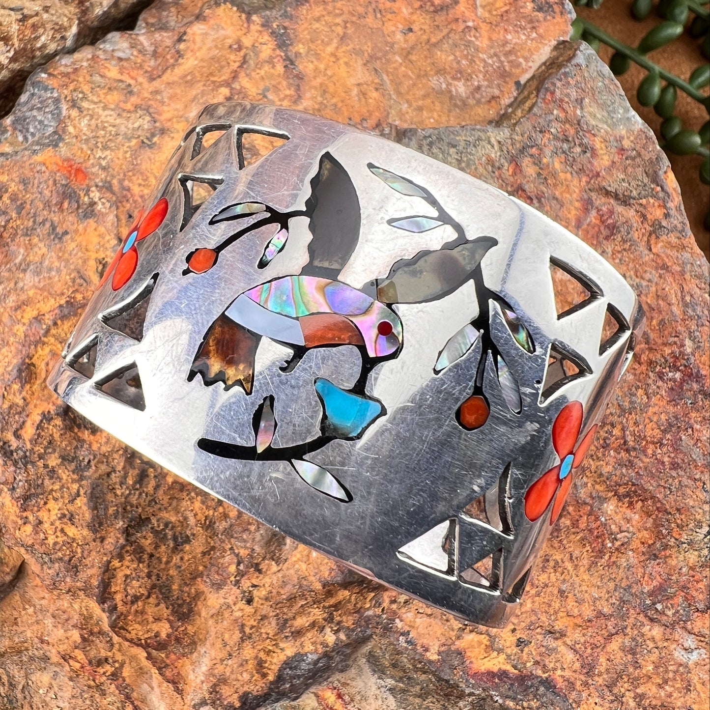 Decorative metal piece with colorful inlay on a stone surface