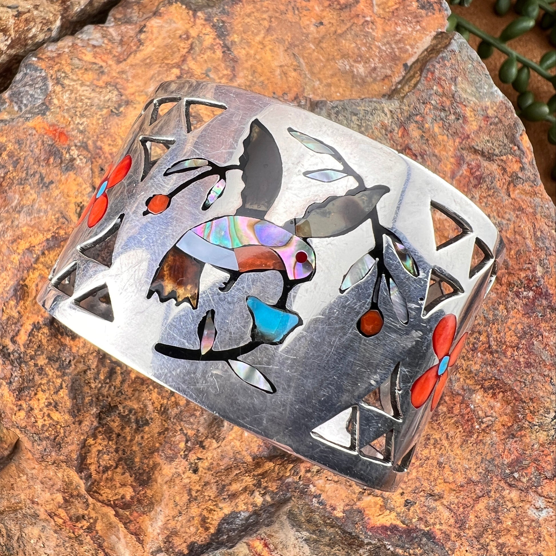 Decorative metal piece with colorful inlay on a stone surface
