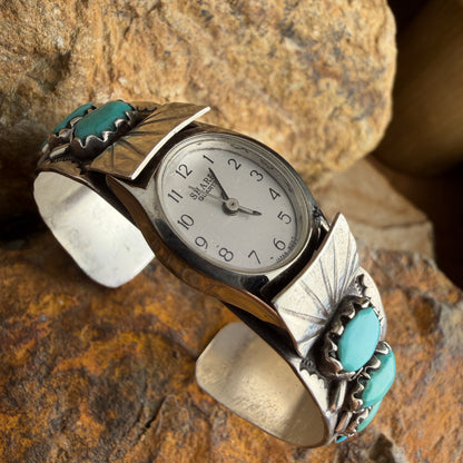 Silver watch with turquoise accents on a stone surface
