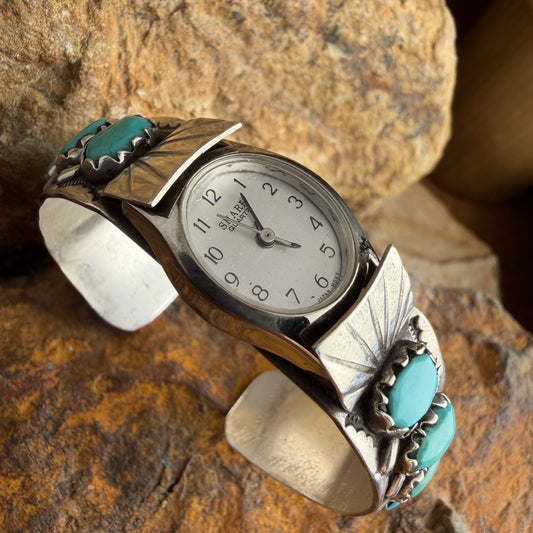 Silver watch with turquoise accents on a stone surface