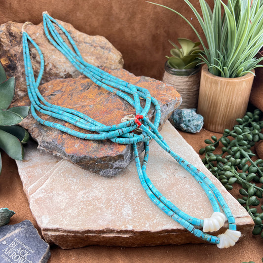 Turquoise beaded necklace on a stone surface with plants in the background