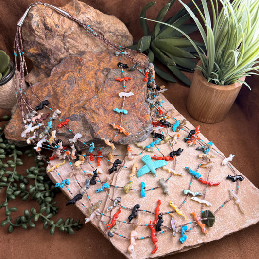 Colorful beaded necklace on a textured stone surface with plants in the background