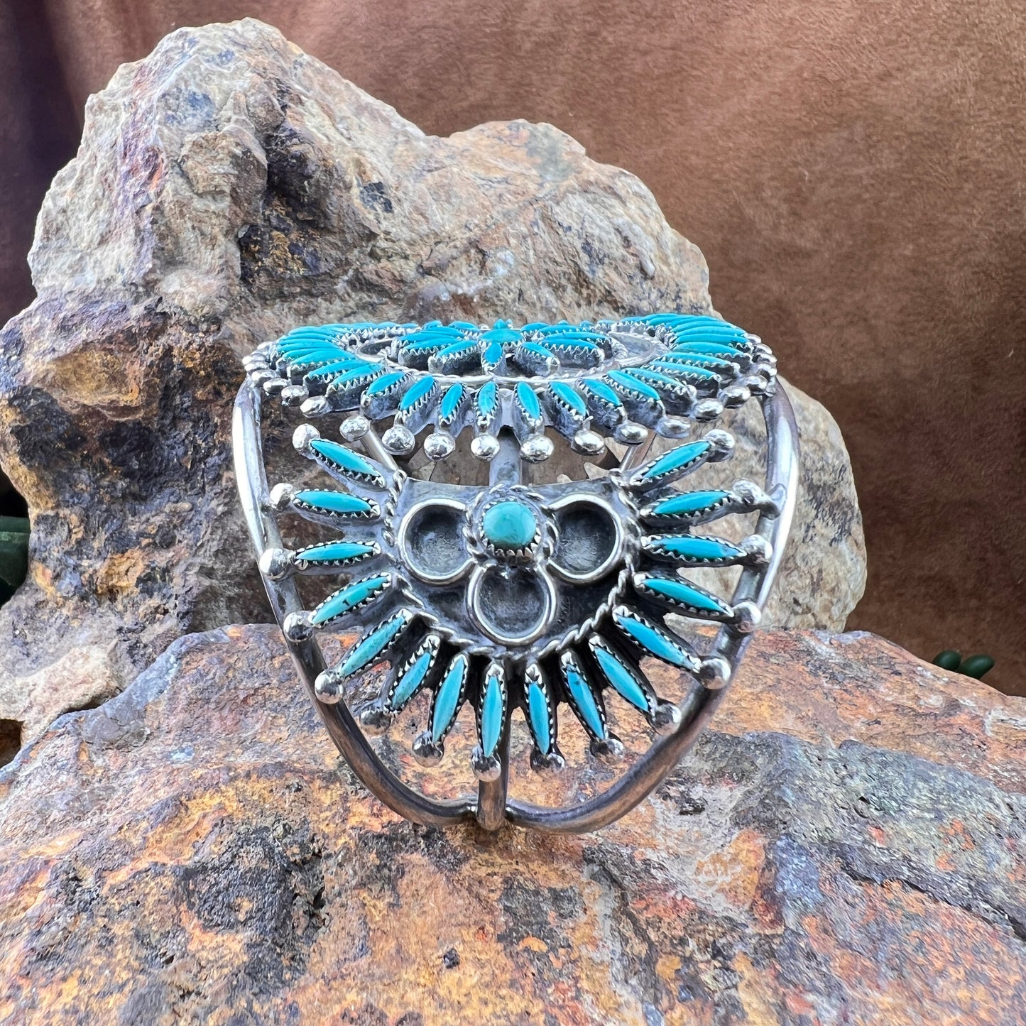 Silver and turquoise bracelet on a rock with a brown background