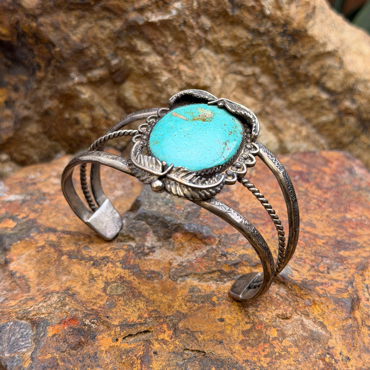 Oval blue-green turquoise cabochon framed by silver leaves and scalloped accents