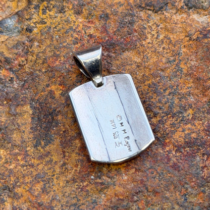 the back of a shield shaped pendant that features the stamps of the maker along with 14k and 925
