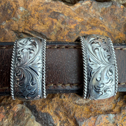 Decorative leather belt with silver buckle on a stone background