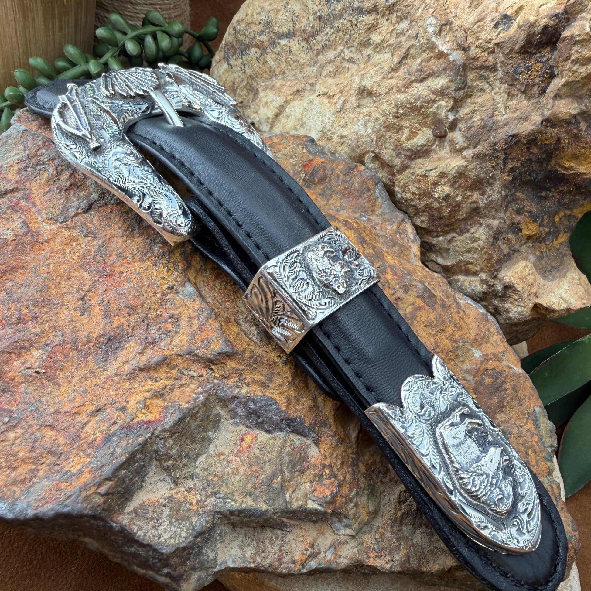 Decorative belt buckle with silver blade and black sheath on a stone surface