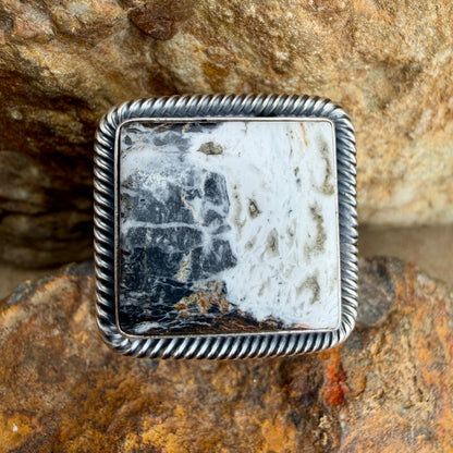 Silver ring with a white and black square stone on a textured stone background