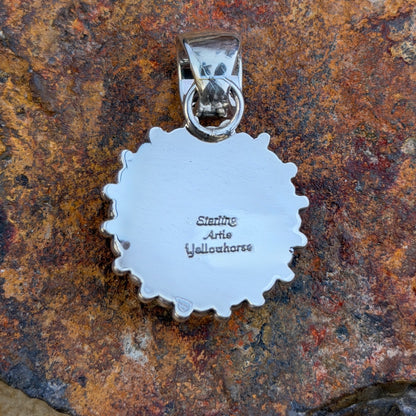 A central dome pendant surrounded by large silver balls accented by smaller one. This pendant is created by Artie Yellowhorse. this picture showcases the hallmarks