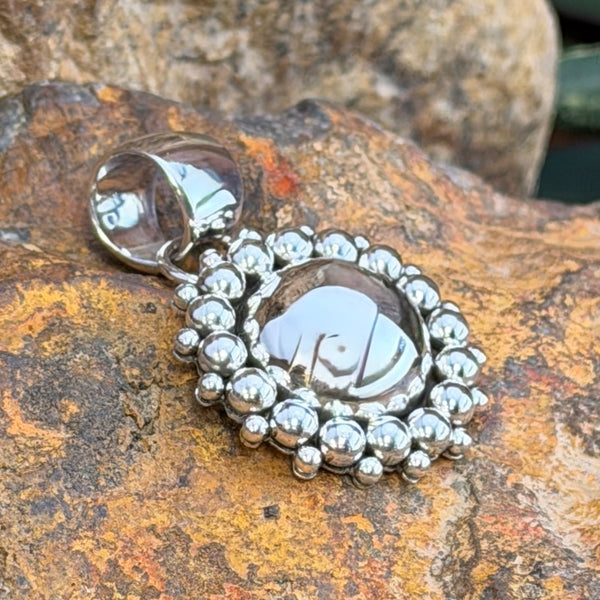 A central dome pendant surrounded by large silver balls accented by smaller one. This pendant is created by Artie Yellowhorse
