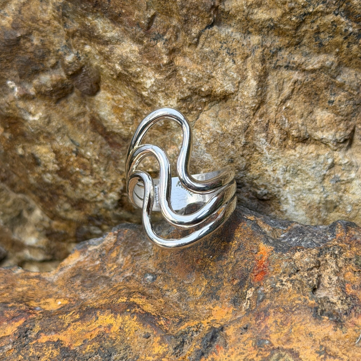 Angled view of Ray Coriz sterling silver smooth wave ring showing open spaces between the bands